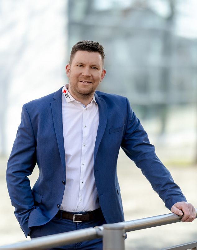 Sebastian Wächter im dunkelblauen Sakko lehnt lächelnd an einem Geländer.